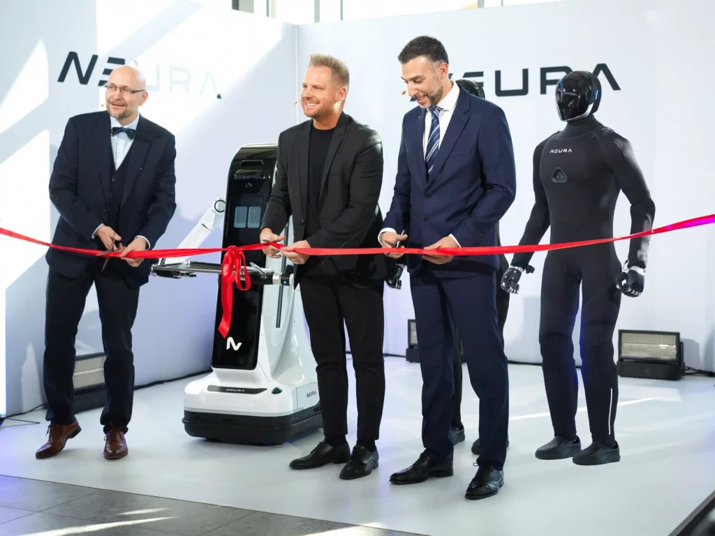 Ribbon-cutting at the TUM RoboGym opening in Munich, with NEURA's MiPA service robot behind and the black textile-skinned 4NE1 Gen 4 humanoid standing at right